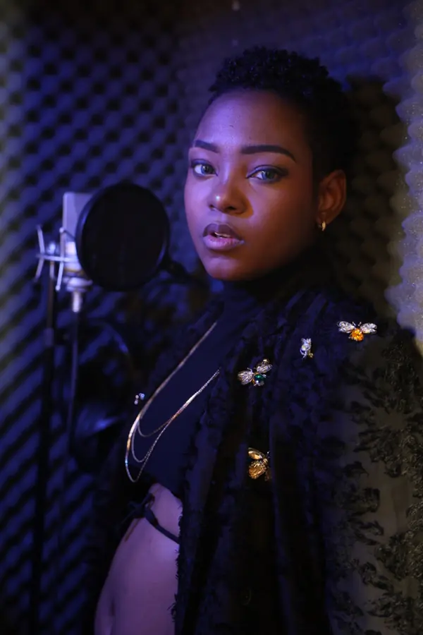 JustBee in a recording booth beside a studio microphone