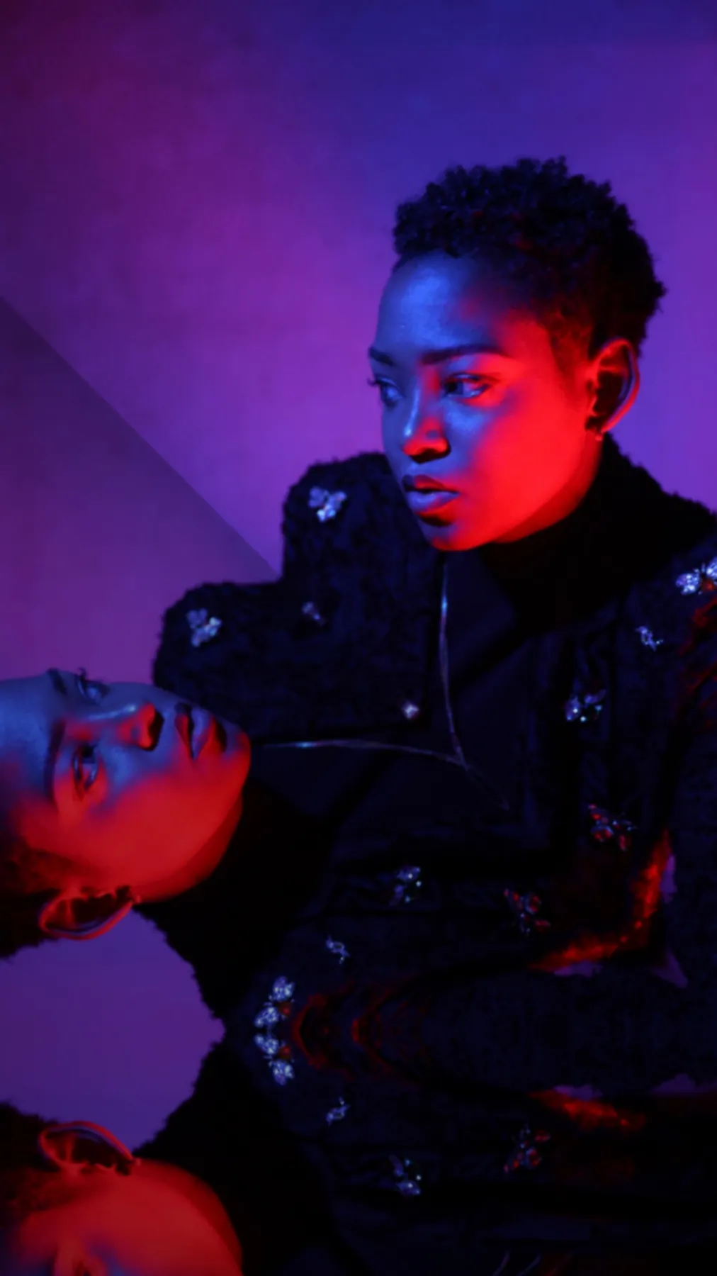 JustBee in purple and red light, wearing a bee-pin jacket