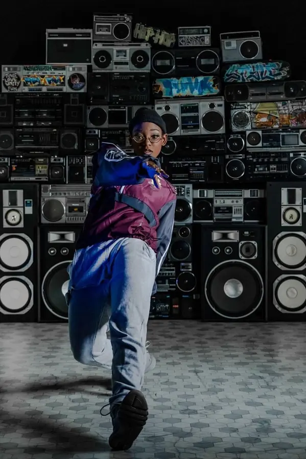 JustBee lunging toward the camera in front of a wall of boomboxes