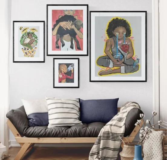 A wall of framed JustBee prints above a sofa