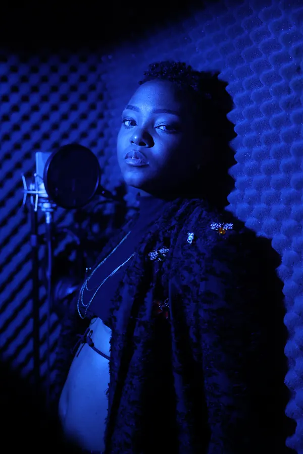 JustBee in a blue-lit recording booth