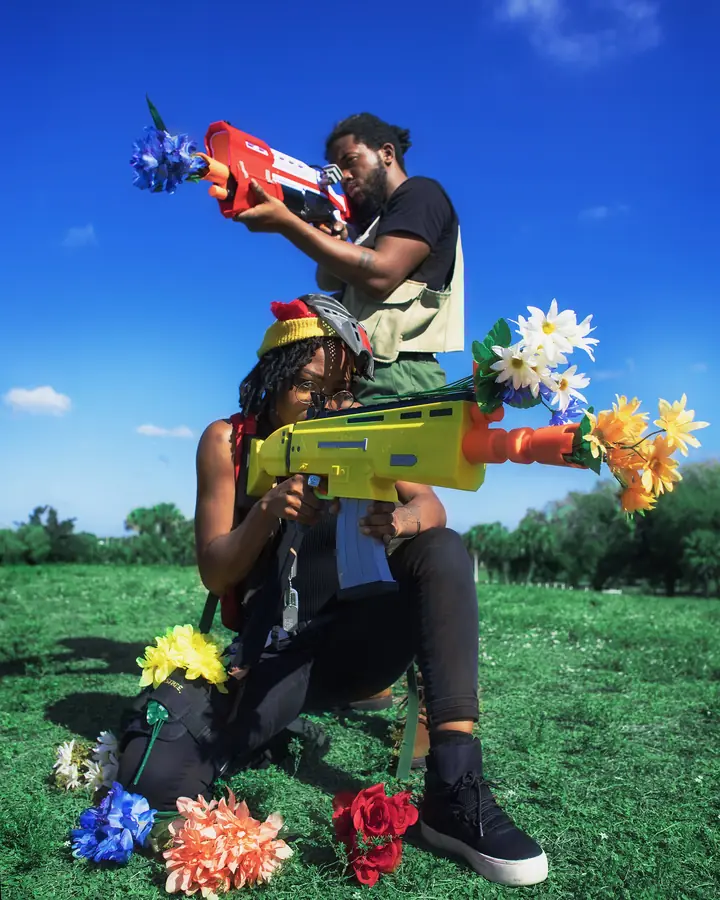 JustBee and a friend with flower-filled toy blasters in a park