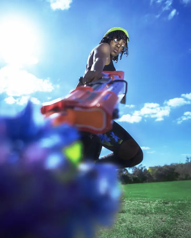 JustBee aiming a flower-filled toy blaster at the sky