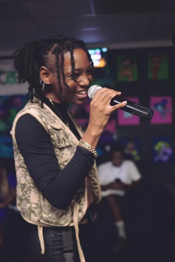 JustBee performing with a microphone in a camo vest