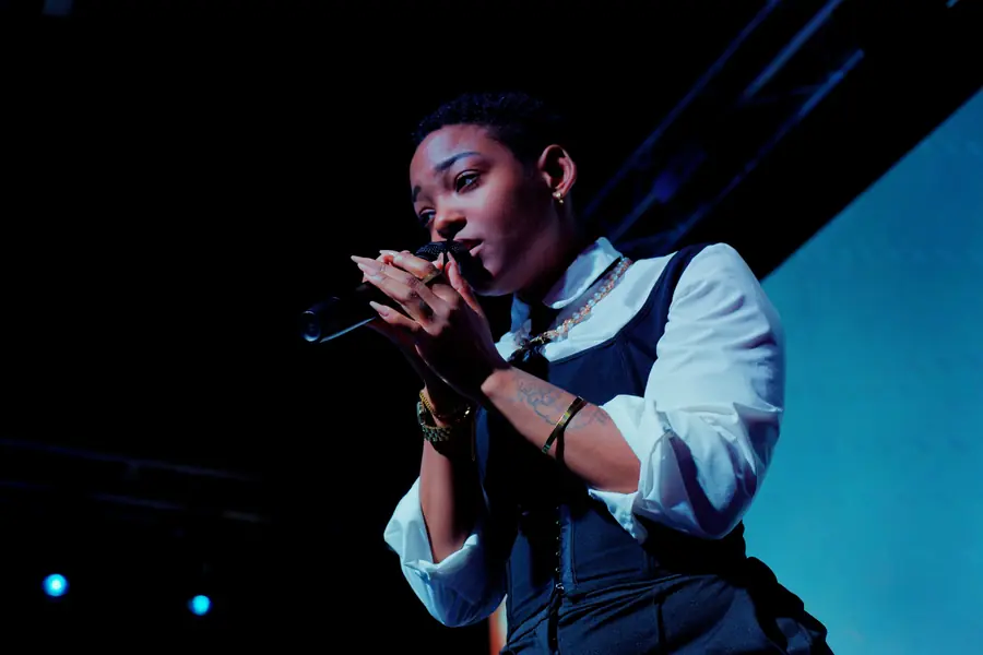 JustBee singing in a white shirt and corset, shot from below