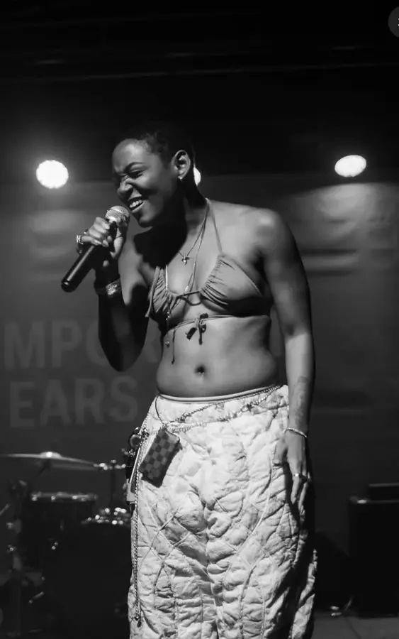 JustBee laughing mid-song on stage, black and white