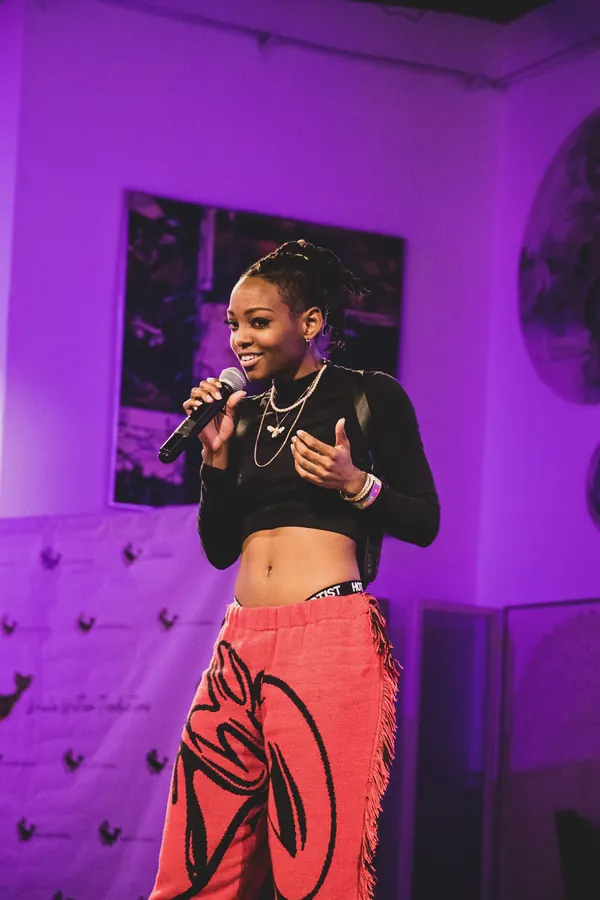 JustBee smiling on stage with a microphone