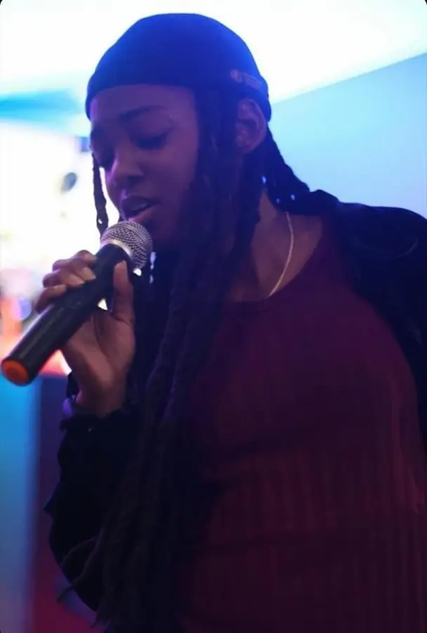 JustBee singing with her eyes closed in a velvet top