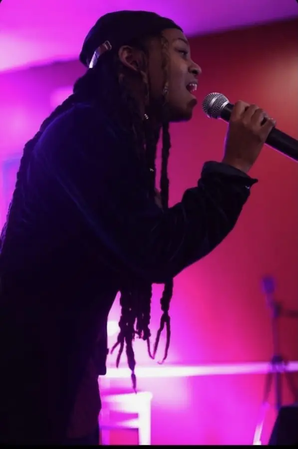 JustBee singing in profile under pink light