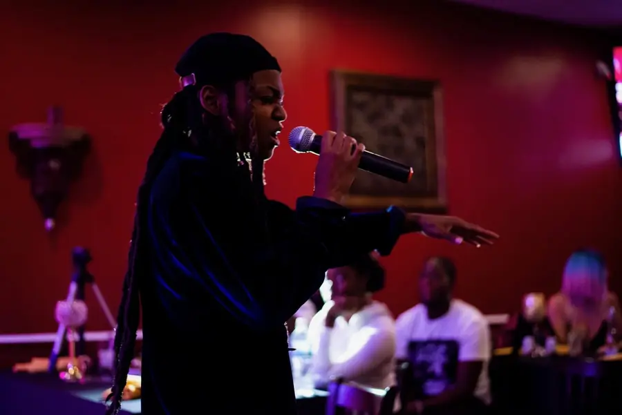 JustBee performing to a seated crowd in a red room