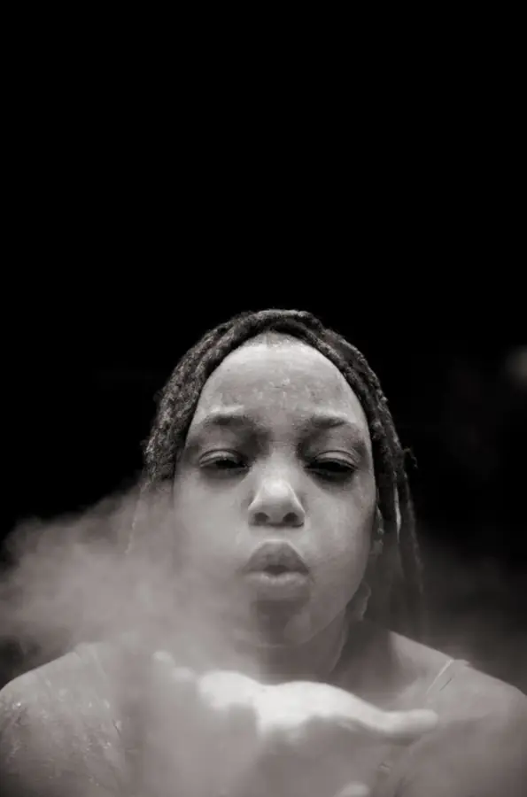 JustBee blowing powder from her hands, black and white