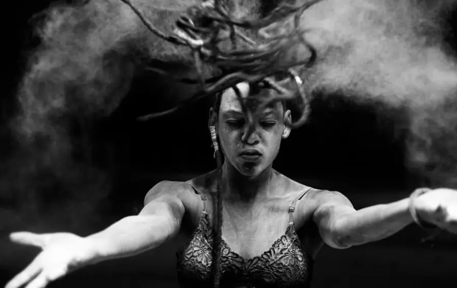 JustBee flipping her locs through a cloud of powder, black and white