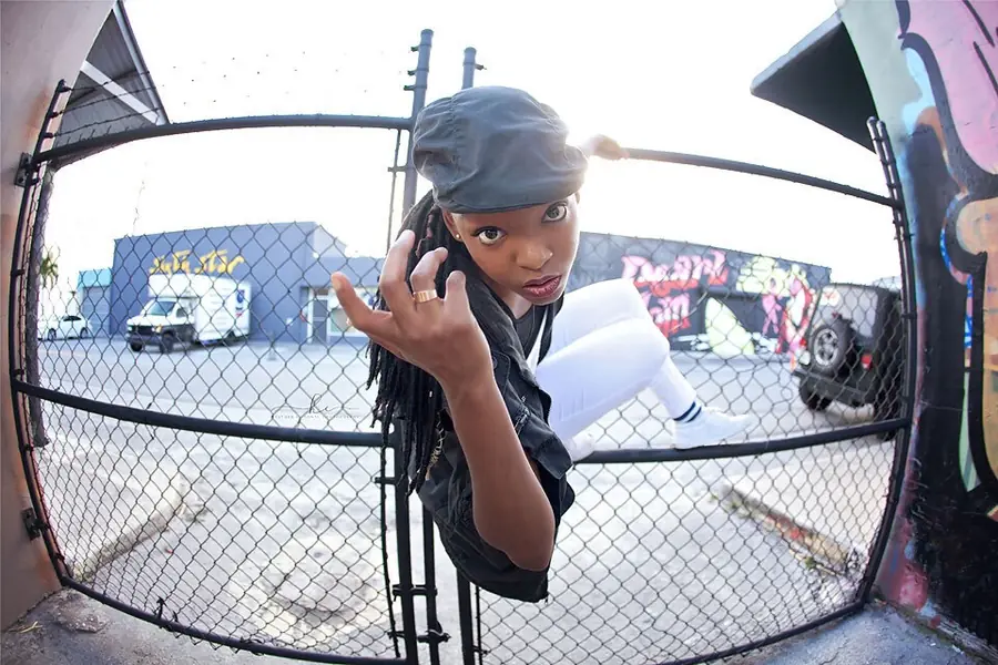 JustBee climbing a chain-link gate, fisheye shot