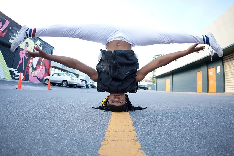 JustBee in a headstand split on a painted road line