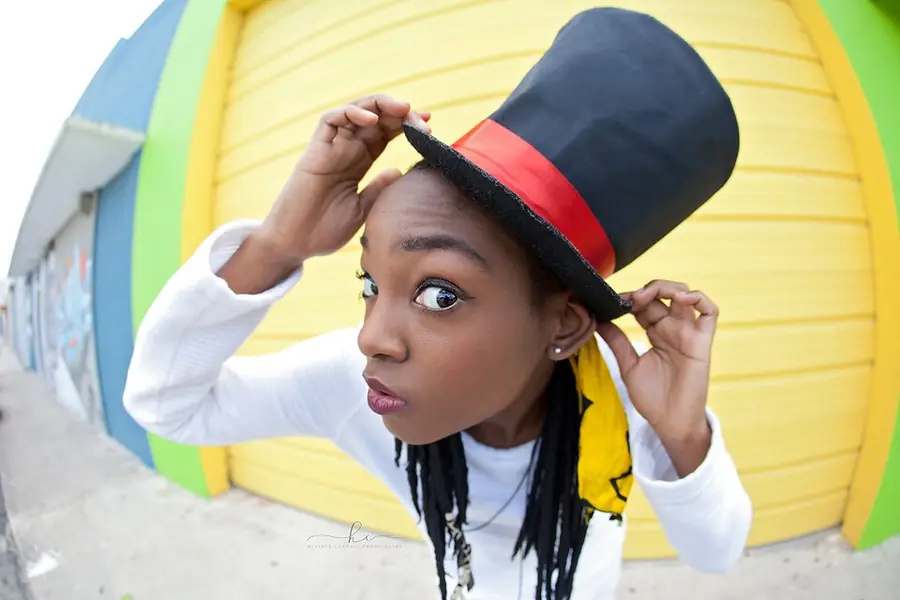 JustBee tipping a tall top hat against a yellow garage door