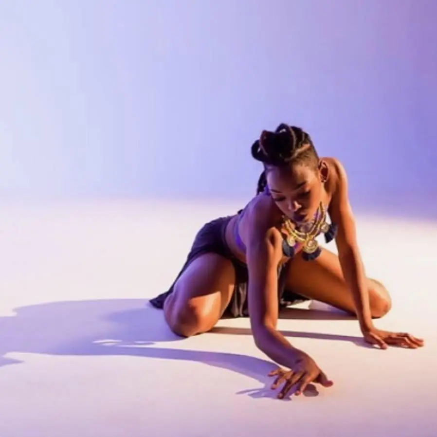 JustBee reaching across the floor in purple light