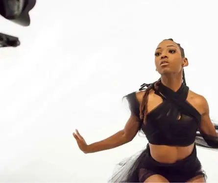 JustBee in black tulle mid-movement in a white studio