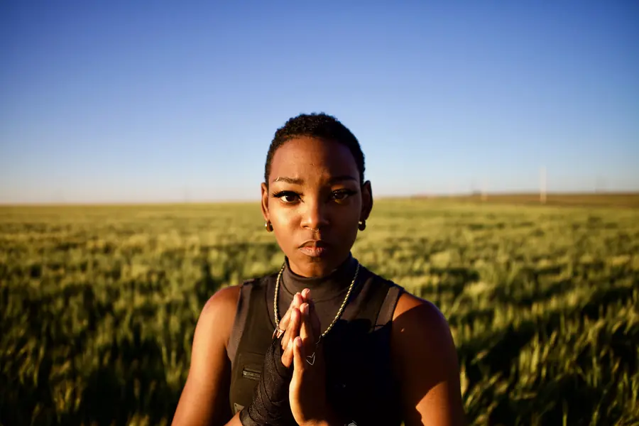 JustBee with hands pressed together in a wheat field
