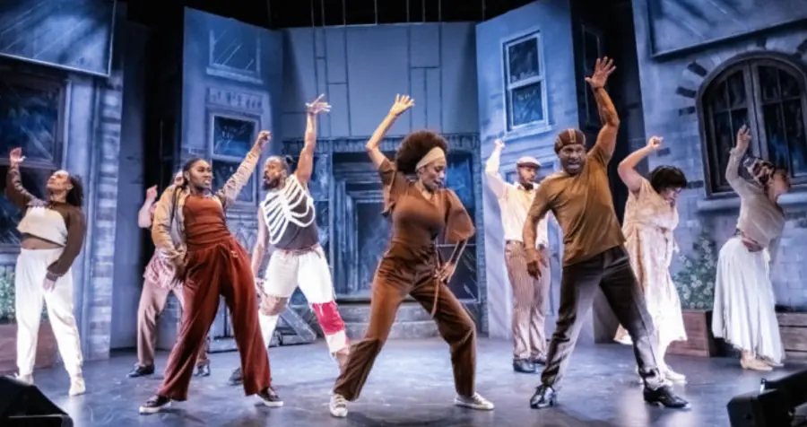 The ensemble of Legends Who Rock and Inspire dancing on a city-street set