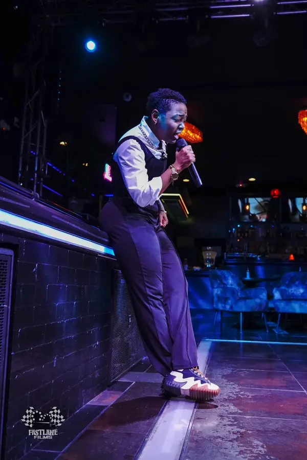 JustBee singing at Sweet Serenade, leaning against the stage edge
